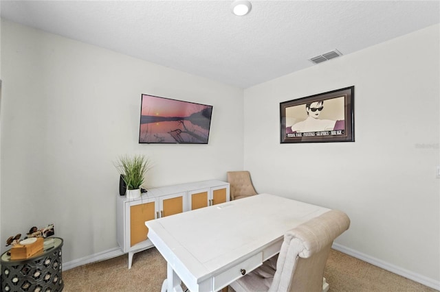 carpeted dining room featuring a textured ceiling