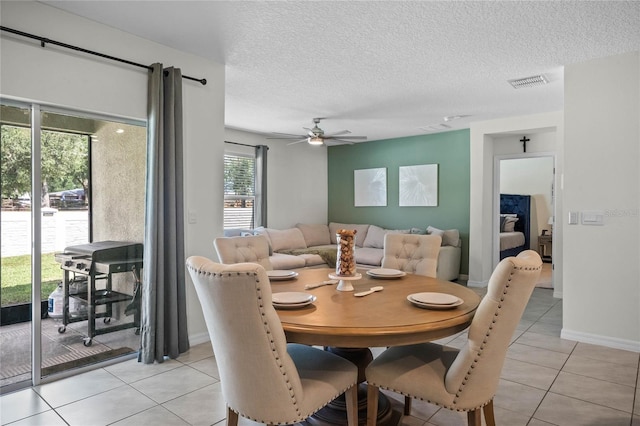 tiled dining area with ceiling fan, a textured ceiling, and a wealth of natural light