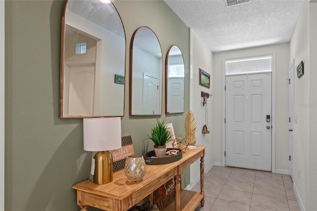 foyer entrance featuring light tile patterned floors and a textured ceiling