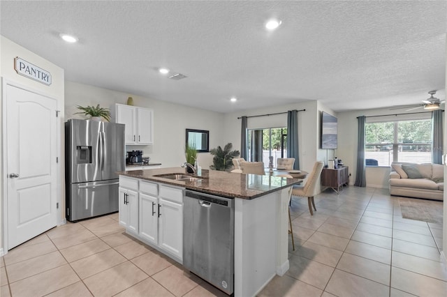 kitchen featuring light tile patterned flooring, sink, a center island with sink, stainless steel appliances, and white cabinets