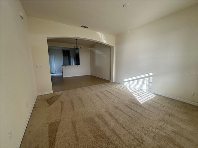 carpeted spare room featuring a chandelier