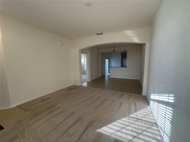 carpeted spare room featuring a notable chandelier