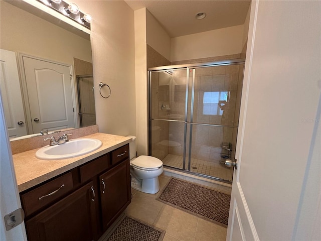 bathroom featuring tile patterned floors, vanity, toilet, and walk in shower