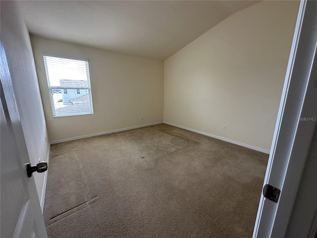 carpeted spare room with vaulted ceiling