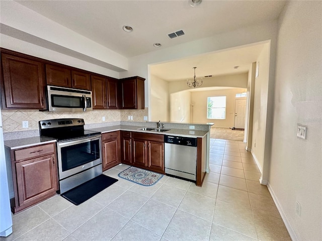 kitchen featuring stainless steel appliances, sink, light tile patterned floors, an inviting chandelier, and hanging light fixtures