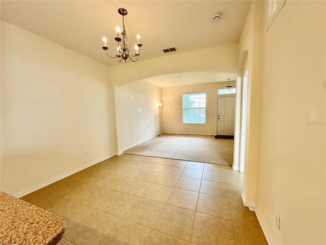 empty room featuring light tile patterned floors and an inviting chandelier