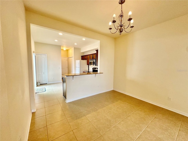 interior space with kitchen peninsula, pendant lighting, light tile patterned floors, a notable chandelier, and a breakfast bar area