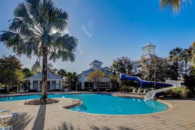 community pool with a water slide and a patio area