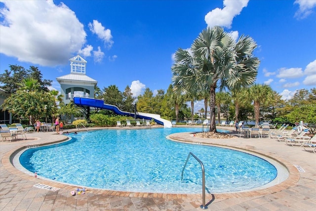 community pool featuring a water slide and a patio