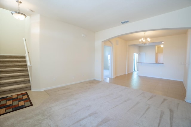 carpeted spare room featuring arched walkways, visible vents, baseboards, stairway, and an inviting chandelier