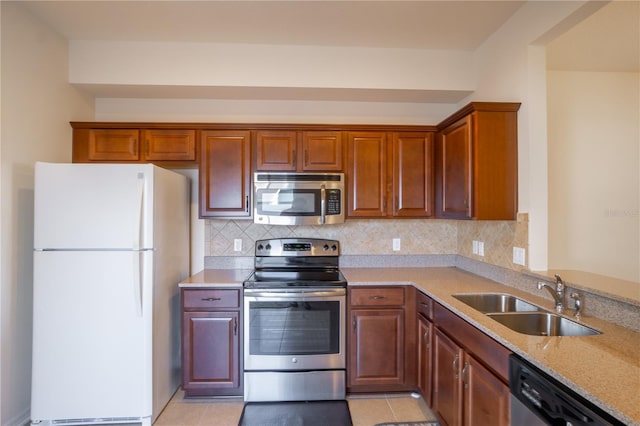 kitchen featuring stainless steel appliances, a sink, backsplash, and light tile patterned floors