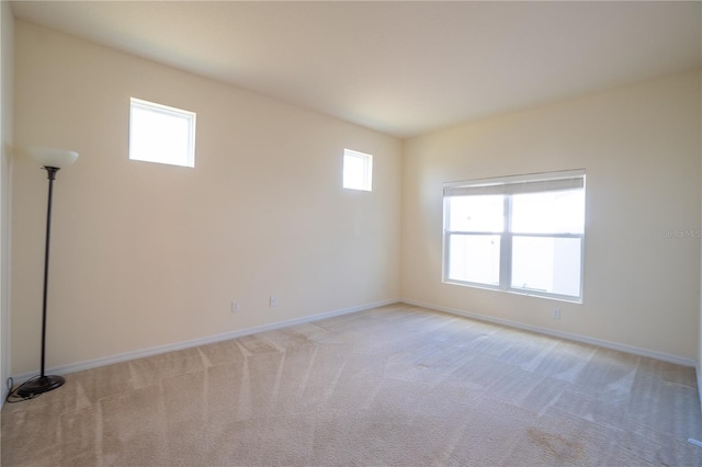 unfurnished room featuring baseboards and light colored carpet