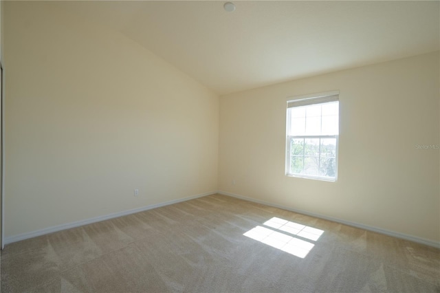 empty room with light carpet, baseboards, and lofted ceiling