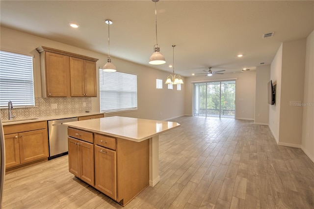 kitchen with light hardwood / wood-style floors, sink, ceiling fan with notable chandelier, stainless steel dishwasher, and a center island