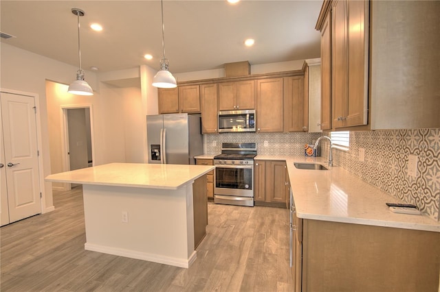 kitchen with stainless steel appliances, a center island, sink, light wood-type flooring, and decorative light fixtures