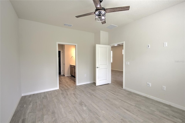 unfurnished bedroom featuring ensuite bathroom, light hardwood / wood-style flooring, a textured ceiling, and ceiling fan