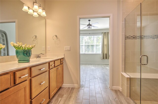 bathroom featuring hardwood / wood-style floors, ceiling fan with notable chandelier, vanity, and a shower with door