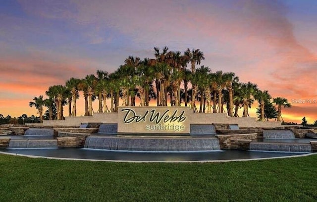 community / neighborhood sign featuring a water view and a yard