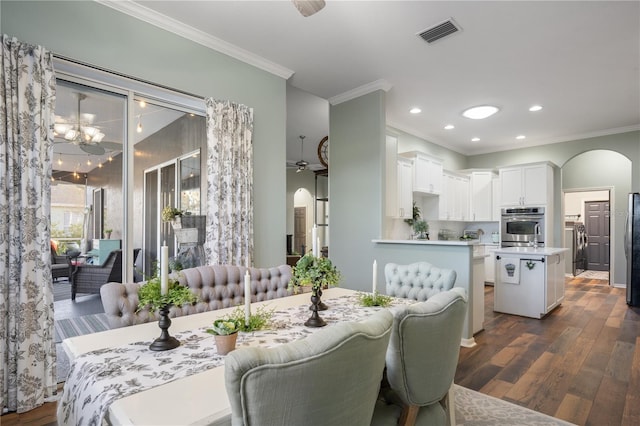 dining area with washer / dryer, dark hardwood / wood-style flooring, ceiling fan with notable chandelier, and ornamental molding