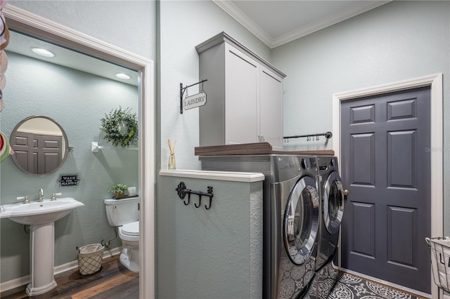 laundry area featuring sink, washer and clothes dryer, dark wood-type flooring, and ornamental molding