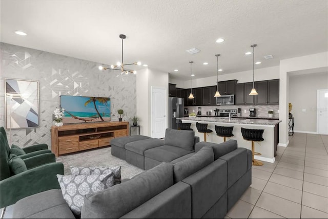 tiled living room with tile walls, a textured ceiling, and a notable chandelier