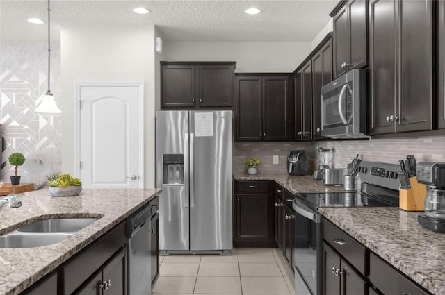 kitchen with appliances with stainless steel finishes, a textured ceiling, light stone counters, and hanging light fixtures