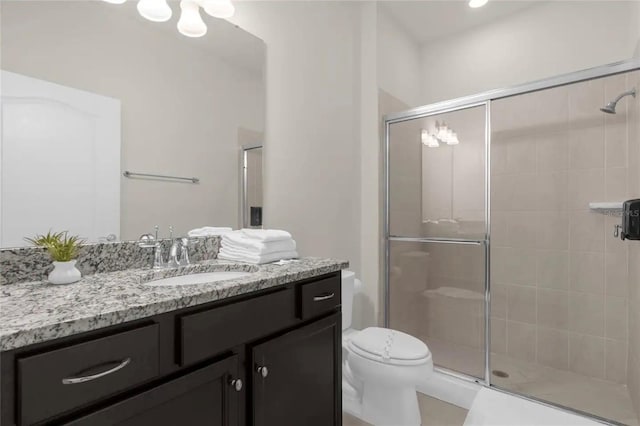 bathroom featuring toilet, vanity, and a shower with door