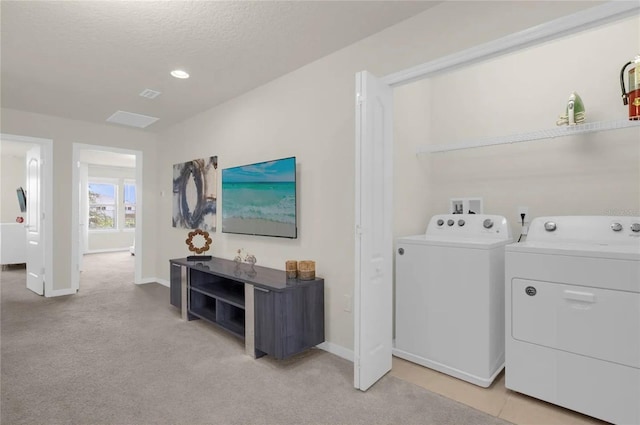 laundry area with a textured ceiling, light carpet, and washer and clothes dryer