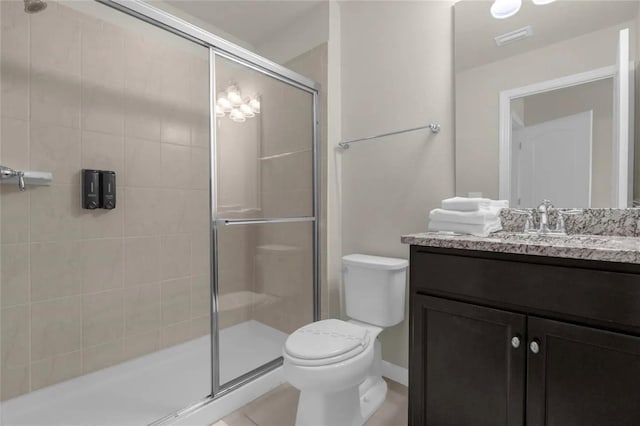 bathroom featuring toilet, vanity, tile patterned flooring, and a shower with door