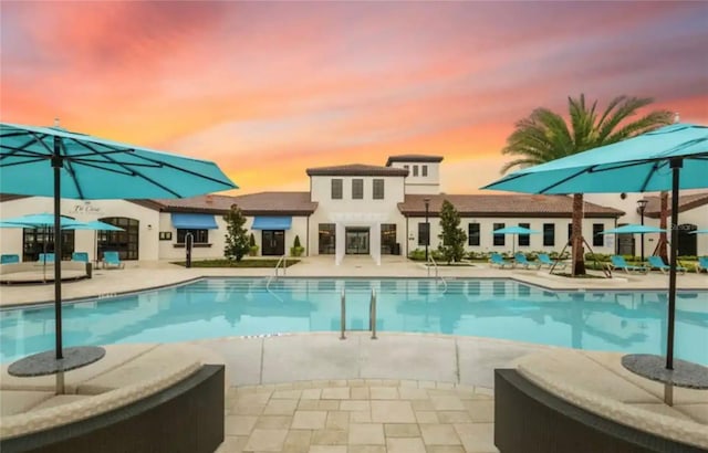 pool at dusk featuring a patio