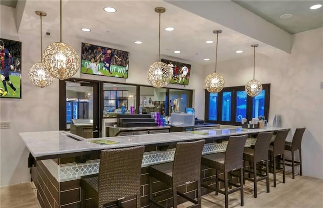 bar featuring light wood-type flooring and decorative light fixtures