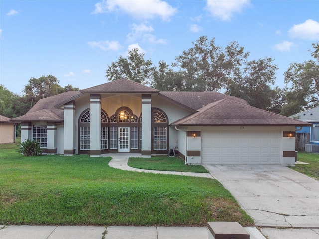 view of front of property with french doors, a garage, central AC unit, and a front lawn