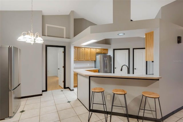 kitchen with high vaulted ceiling, a kitchen bar, a notable chandelier, and stainless steel fridge