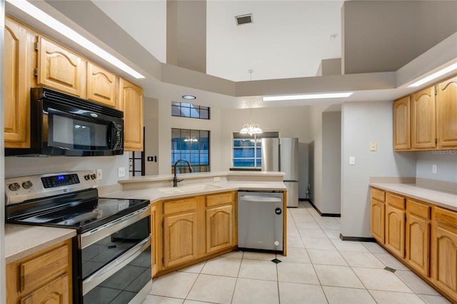 kitchen featuring kitchen peninsula, a chandelier, light tile patterned floors, appliances with stainless steel finishes, and a high ceiling