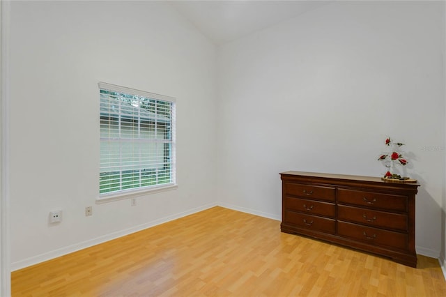 empty room with light hardwood / wood-style flooring and vaulted ceiling