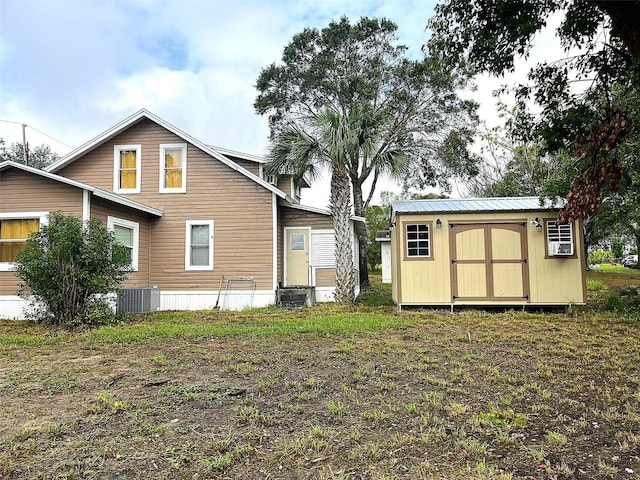 rear view of property with a shed and central AC