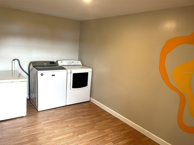 washroom with light hardwood / wood-style flooring and washing machine and clothes dryer