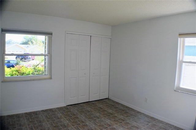 unfurnished bedroom with a closet and multiple windows