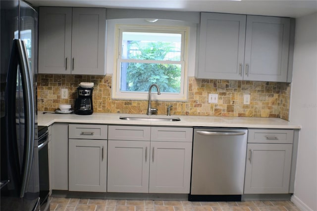 kitchen featuring sink, gray cabinets, dishwasher, tasteful backsplash, and black fridge