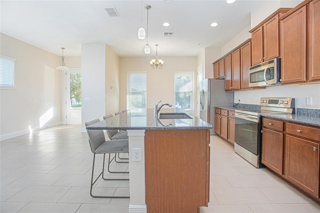 kitchen with stainless steel appliances, plenty of natural light, and a kitchen island with sink