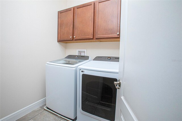 clothes washing area with light tile patterned floors, cabinets, and independent washer and dryer