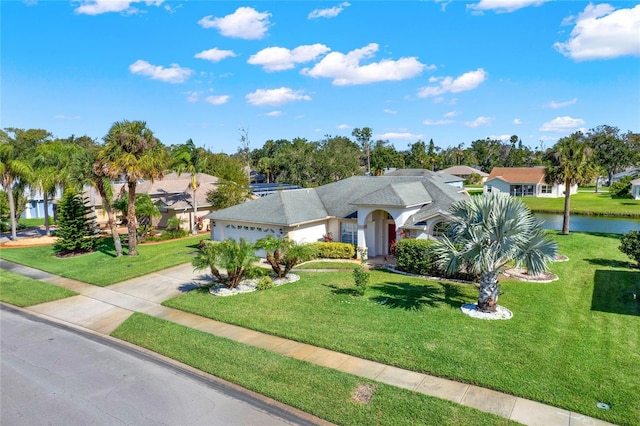 view of front of property with a front yard, a garage, and a water view