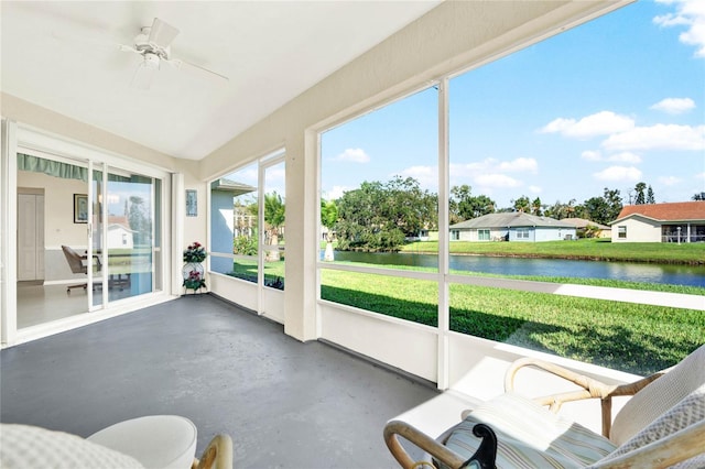 sunroom with ceiling fan and a water view