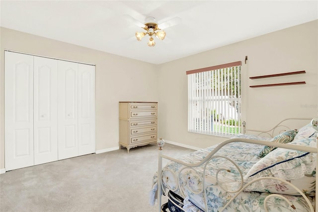 bedroom featuring ceiling fan with notable chandelier, light colored carpet, and a closet