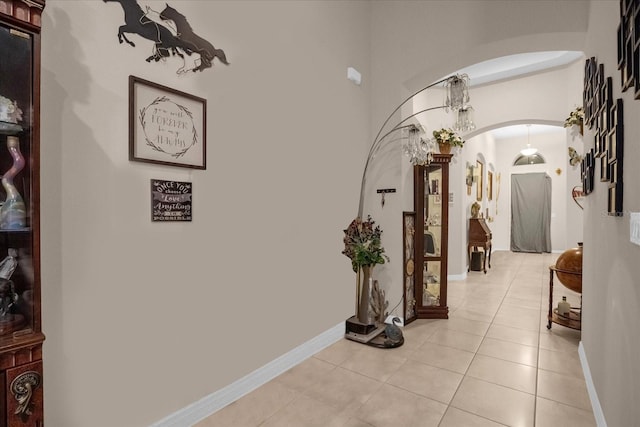 4001 Scarlet Branch Rd, Orlando, FL 32824 - hallway with arched walkways, light tile patterned floors, a chandelier, and baseboards