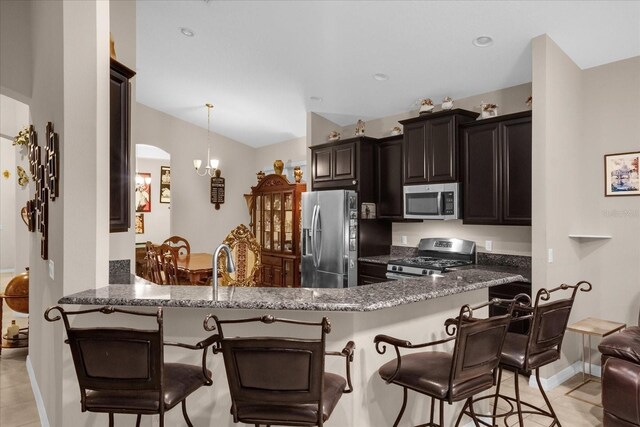 4001 Scarlet Branch Rd, Orlando, FL 32824 - kitchen with appliances with stainless steel finishes, a kitchen breakfast bar, baseboards, dark stone counters, and lofted ceiling