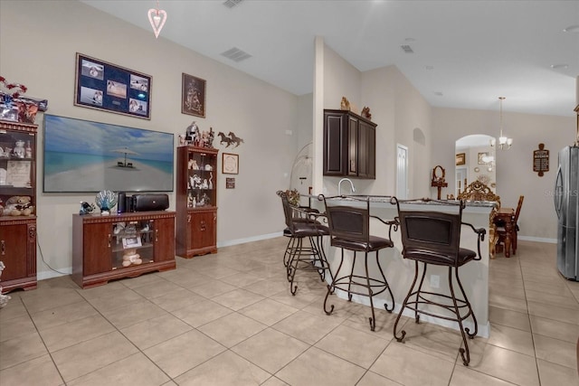 4001 Scarlet Branch Rd, Orlando, FL 32824 - kitchen with arched walkways, a kitchen breakfast bar, vaulted ceiling, light tile patterned flooring, and dark brown cabinets