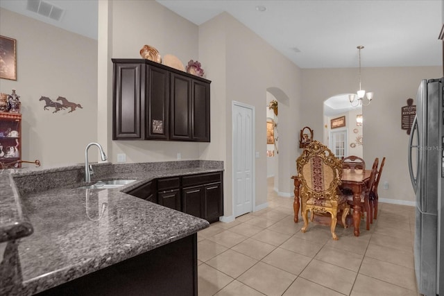 4001 Scarlet Branch Rd, Orlando, FL 32824 - kitchen with a sink, freestanding refrigerator, arched walkways, light tile patterned floors, and dark stone countertops