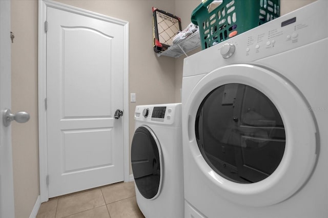 4001 Scarlet Branch Rd, Orlando, FL 32824 - laundry room featuring washer and clothes dryer, light tile patterned flooring, and baseboards