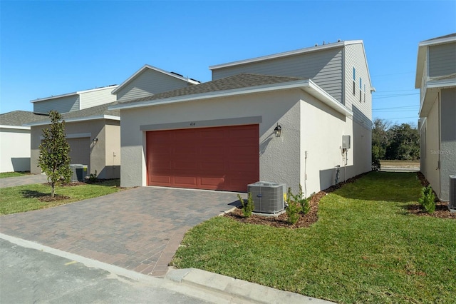 view of front of home with central AC, a garage, and a front yard